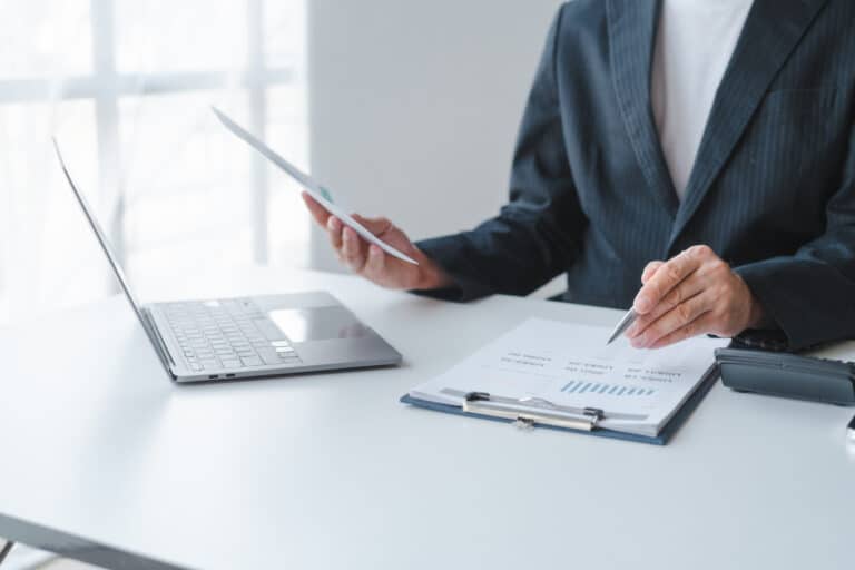 Young handsome asia business man in formal suit working with monthly report balance sheet and yearly tax of accounting to verify the account by an authorized auditor